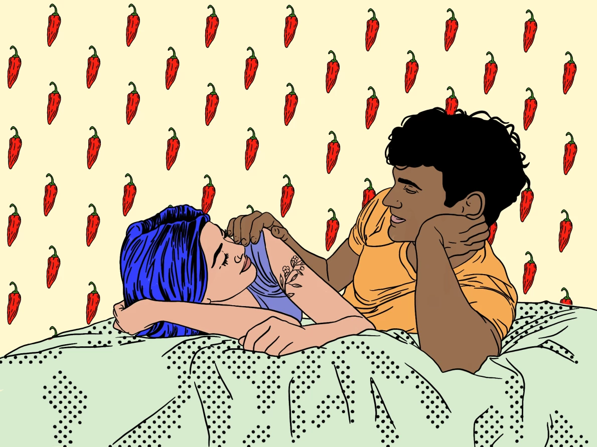 A couple looking at each other on a bed with chili peppers in the background