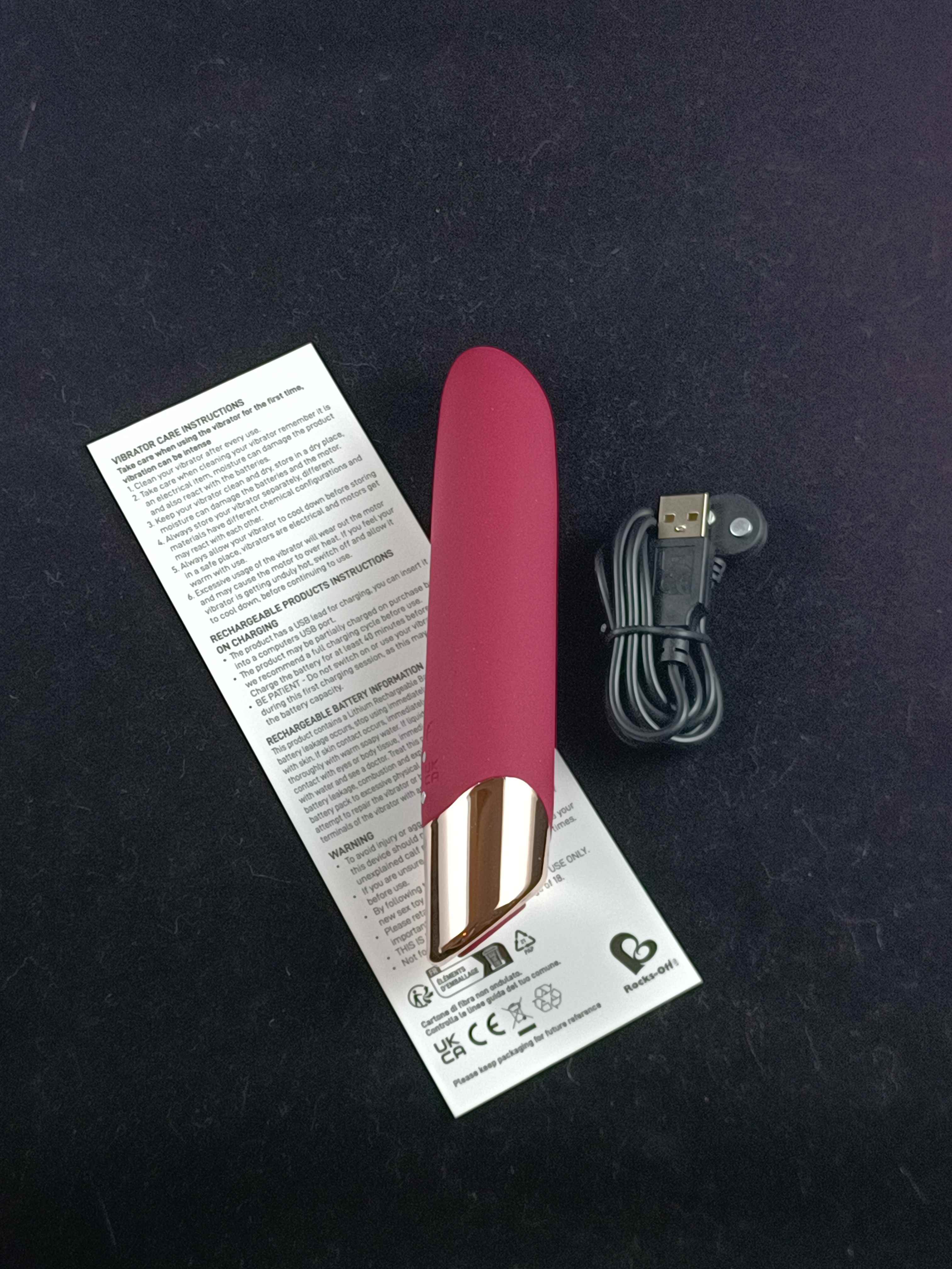 Pictured is the Rocks-Off Chaiamo Vibrator, charger, and instruction sheet.