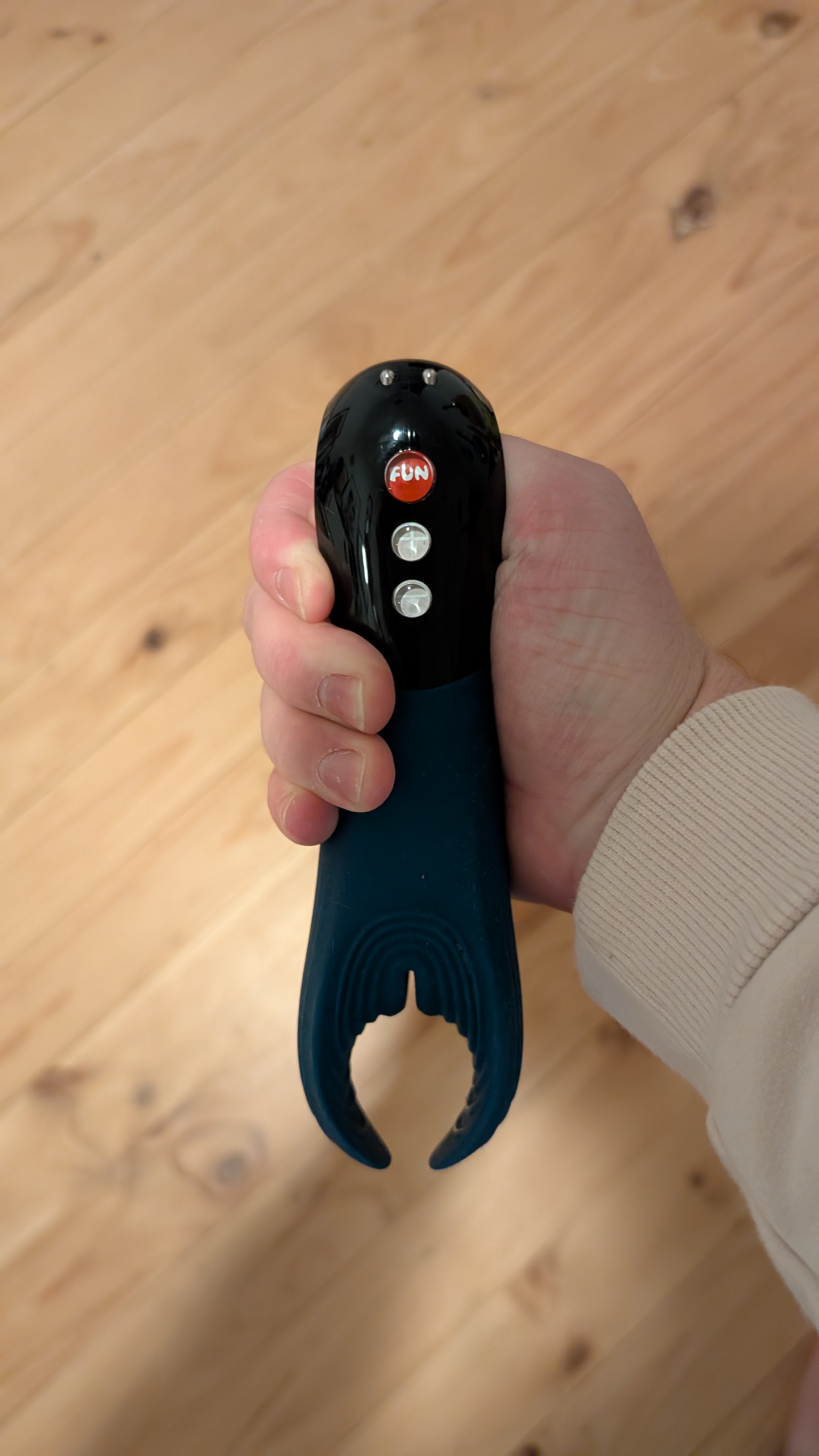 Fun Factory Manta frenulum massager held via the thumb hole at the base.
