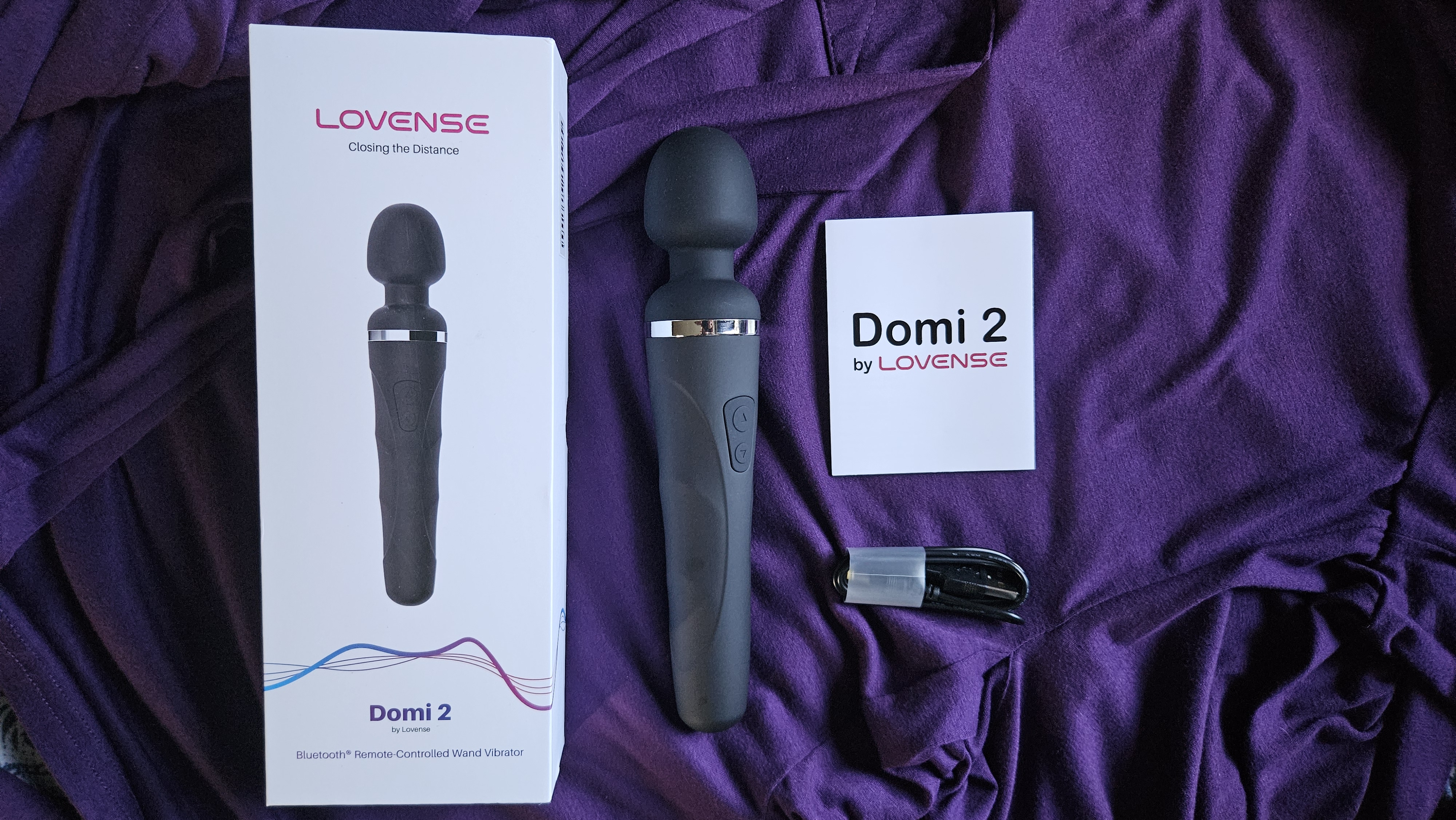 Pictured is the Lovense Domi 2 next to its packaging and charging cable. Pictured is the Lovense Domi 2 next to its packaging and charging cable.