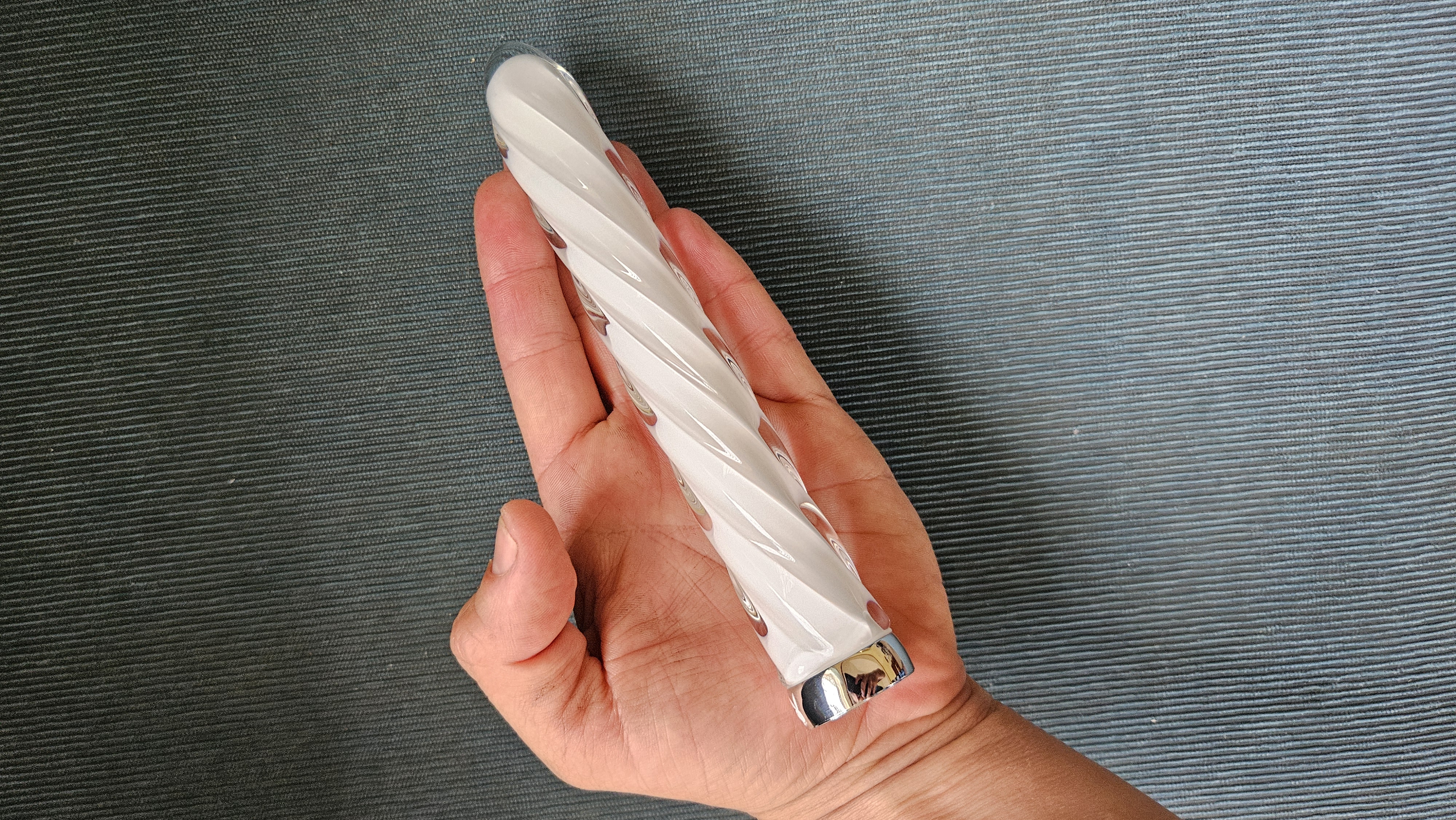 Playboy Pleasure In A Twist Glass Vibrator held in hand for size reference.