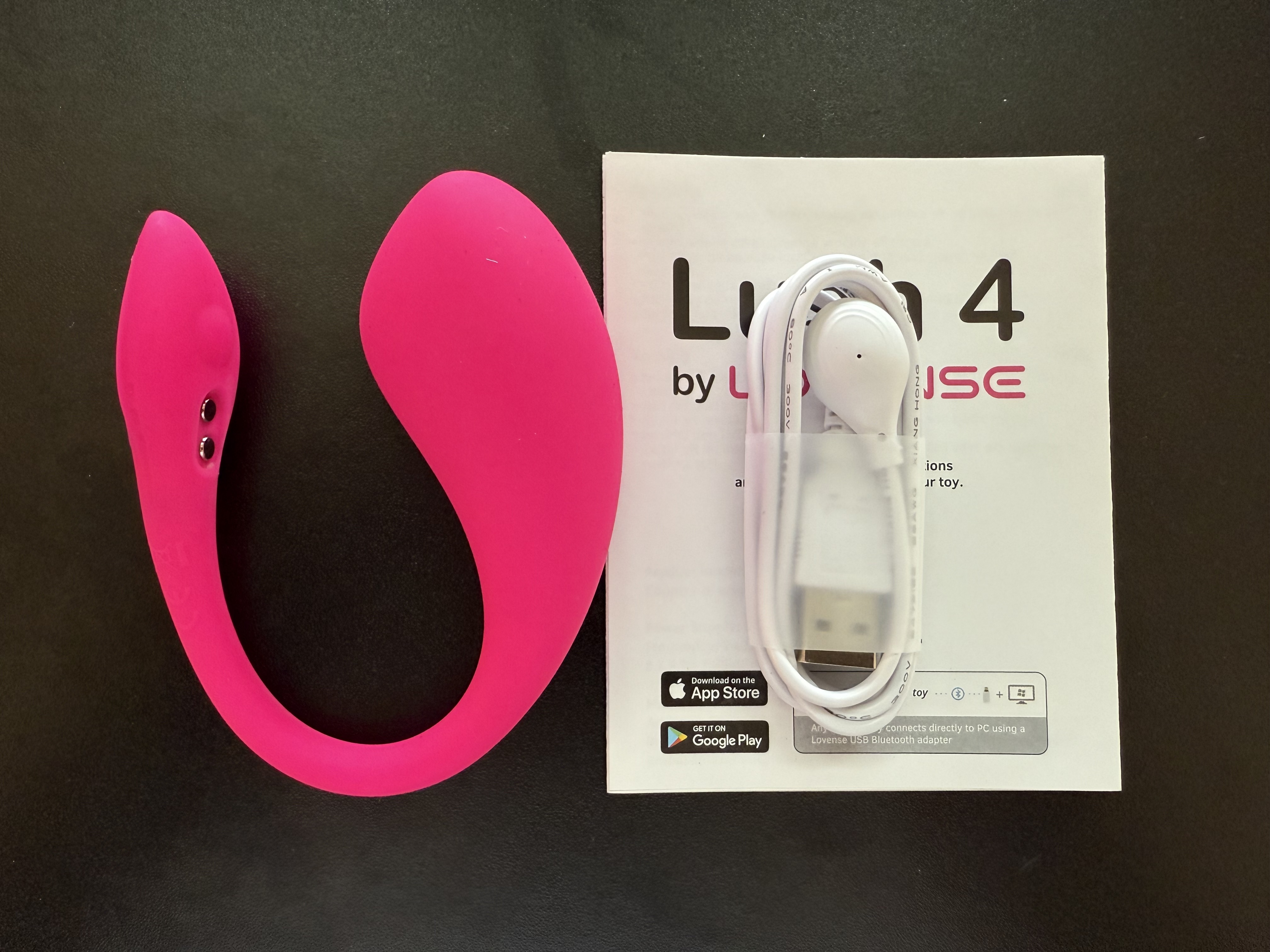 Pictured is the Lovense Lush 4 with its charging cable and user manual.